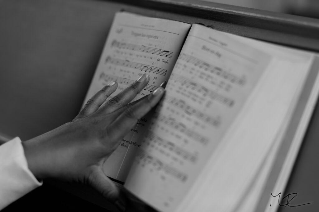 En flicka håller handen på en uppslagen psalmbok