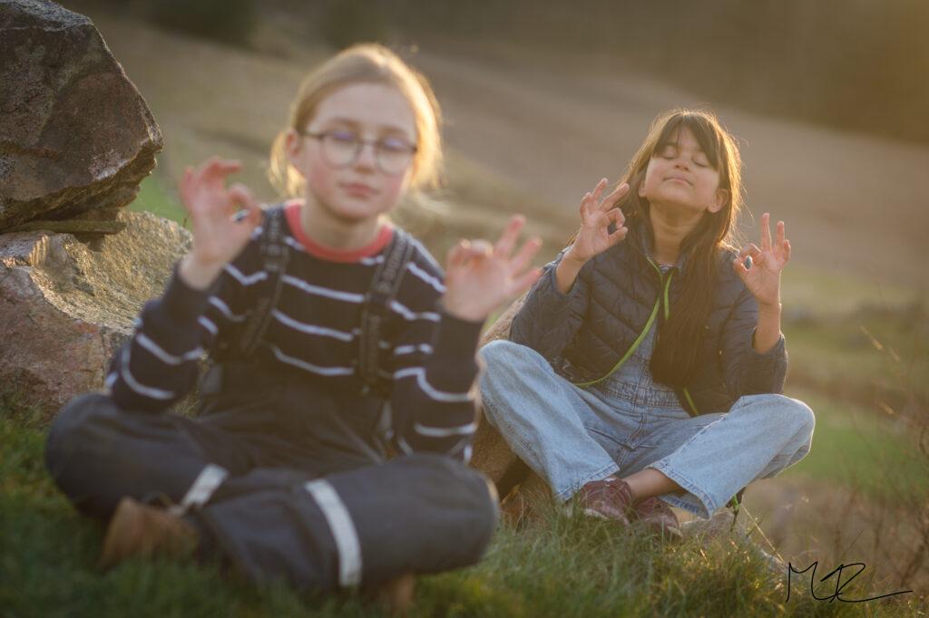 Två flickor mediterar i solnedgången