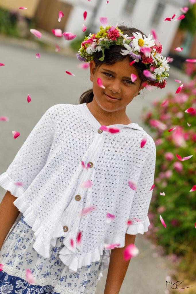 En flicka i ett hav av flygande blad, med en midsommarkrans på huvudet